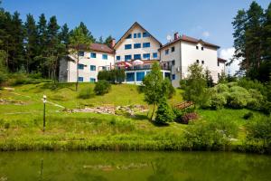 una casa grande en una colina junto a un lago en Hotel Perła Bieszczadów Geovita en Czarna