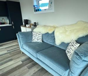 um sofá azul numa sala de estar com um pêlo falso em The Grimsay Cabin em Carinish