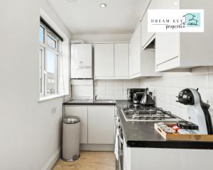 a kitchen with white cabinets and a stove top oven at One Bedroom Apartment by Dream Key Properties Short Lets & Long Lets Uxbridge with Free Wi-fi - 5 in Uxbridge