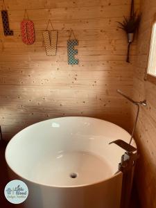 bañera blanca en una habitación con pared de madera en Little Wood Lodges Insolites, en Bailly-aux-Forges