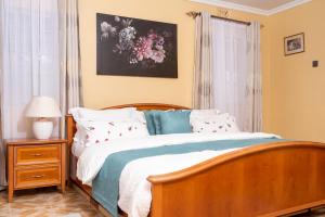sypialnia z drewnianym łóżkiem z poduszkami i oknem w obiekcie Augustine Cosy Homes w mieście Nakuru