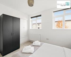 Spacious Two Bedroom Apartment by Dream Key Properties Short Lets & Long Lets Uxbridge- 1 في أوكسبريدج: غرفة نوم بيضاء مع خزانة سوداء وكرسي أبيض