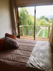 a bed in a room with a large window at Vistaranco Costanera in Lago Ranco