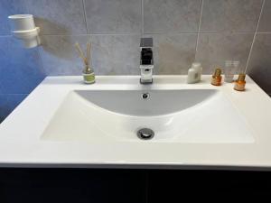 un lavabo blanco en un baño con algunos artículos. en [Chi Ama il Mare] Appartamento, en Latina