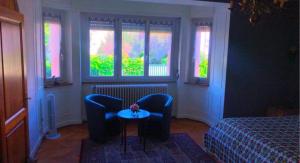 コルマールにあるGîte "La Baloise"の椅子2脚、テーブル、窓が備わる客室です。