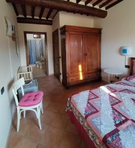 a bedroom with a bed and a chair and a table at Ospitalità Rurale l'Uccelliera in Lucca