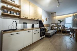 a kitchen with white cabinets and a living room at WiguryTower Apartaments 74' in Łódź