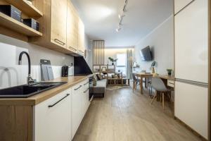 une cuisine avec des placards blancs et une salle à manger dans l'établissement WiguryTower Apartaments 74', à Łódź