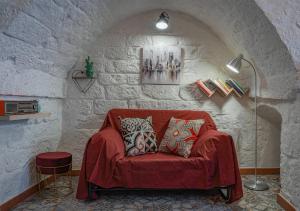 sala de estar con sofá rojo en una pared de piedra en Casa Vacanze “House on the Left”, en Ceglie Messapica