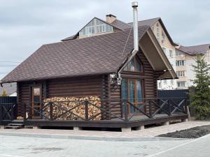 a log cabin with a porch and a roof at Затишний котедж в Білогородці in Belogorodka
