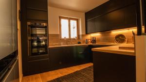 a large kitchen with black cabinets and a window at Chalet Peak Noir entier 12pers - Cosy House Peak Noir for 12people in Le Monêtier-les-Bains