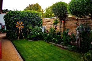 a garden with a lawn and a fence with a windmill at Barlin Guesthouse in Randfontein