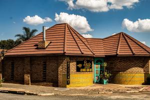 een klein bakstenen gebouw met een gele deur bij Barlin Guesthouse in Randfontein