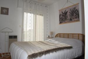 een witte slaapkamer met een bed en een raam bij Côte et Vie - appartement et garage in Saint-Gilles-Croix-de-Vie