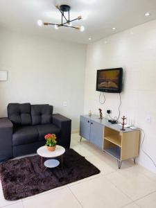uma sala de estar com um sofá e uma televisão na parede em Flat Turmilagres Bontempo em São Miguel dos Milagres