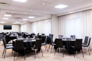a conference room with tables and chairs and a screen at AC Hotel by Marriott Manchester Salford Quays in Manchester