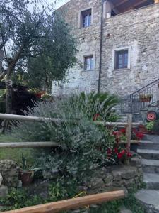 un bâtiment en pierre avec une bande de plantes devant lui dans l'établissement Casa Luci, vista mare, à Vezzi Portio
