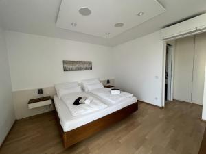 Dormitorio blanco con cama con almohadas blancas en Luxusappartement mit Garage im Zentrum, en Wiener Neustadt