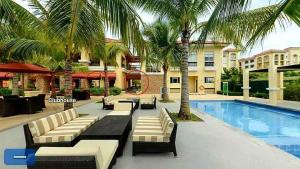 a resort with a swimming pool and palm trees at CasaMia Studio Sanremo Oasis Cebu in Talisay
