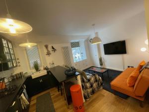 uma sala de estar com um sofá laranja e uma cozinha em Glen Ness Apartment in tranquil area of city centre em Inverness