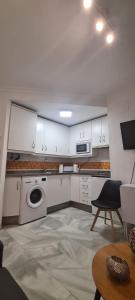 eine Küche mit weißen Schränken, einer Waschmaschine und einem Trockner in der Unterkunft Apartamento a 2 minutos de la playa y centro in Fuengirola