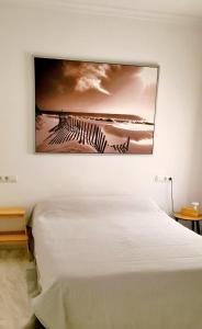 ein Gemälde, das an einer Wand über einem Bett hängt in der Unterkunft Apartamento a 2 minutos de la playa y centro in Fuengirola