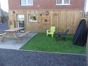 een picknicktafel en stoelen voor een hek bij La tanière des oursons in Aywaille