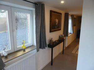 a living room with two windows and a table at La tanière des oursons in Aywaille