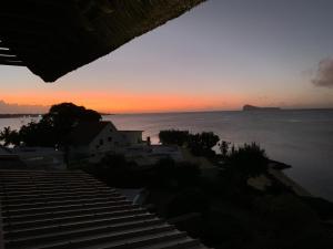 a sunset over the ocean with a house on the beach at Luxury beachfront villa with private pool - Jolly's Rock in Calodyne