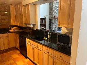 cocina con armarios de madera y encimera negra en Full loft-style apartment near Omni en New Haven