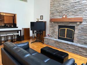 a living room with a leather couch and a stone fireplace at Full loft-style apartment near Omni in New Haven