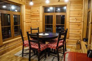 a dining room with a table and chairs and windows at Zemene in Bauska