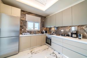 a kitchen with white cabinets and marble counter tops at Thomas Villa Hersonissos - Private Pool - Sleeps 7 in Hersonissos