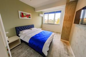 a bedroom with a blue bed and a window at Central Bliss in Suceava