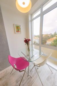 une table en verre et une chaise rose dans une chambre avec fenêtre dans l'établissement Central Bliss, à Suceava