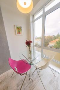 a glass table and a pink chair in a room with a window at Central Bliss in Suceava