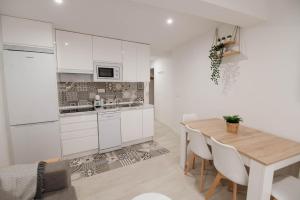 a kitchen and dining room with white cabinets and a wooden table at Apartamentos Turísticos A Tu Verita in Jaraiz de la Vera