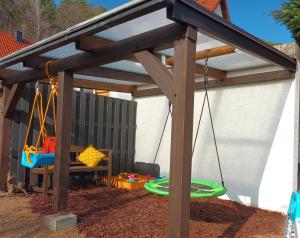 a wooden pergola with a swing and a playground at Lachberg9 in Dahn