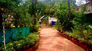 ogród z chodnikiem z roślinami i płotem w obiekcie Stan-Inn, North Goa, Vagator, with strong WIFI,free private parking & kitchen, Can Cook where you stay w mieście Vagator