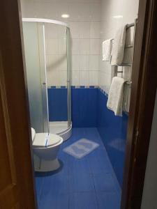 a blue bathroom with a toilet and a shower at Готель Корнет in Umanʼ