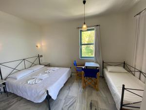 a bedroom with two beds and a desk and a window at Hotel Plakures in Falasarna