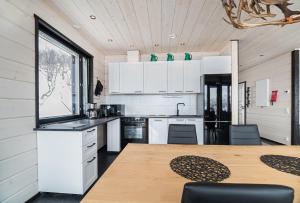 eine Küche mit weißen Schränken und einem Holztisch in der Unterkunft Korppi Mökki in Kilpisjärvi