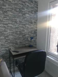 a desk with a chair in front of a brick wall at Maison ville 50m2 5 personnes in Saint-Pierre-des-Corps