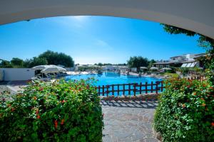 - une piscine dans un complexe avec quelques fleurs dans l'établissement Hotel Resort Nuraghe Arvu, à Cala Gonone