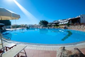 une grande piscine bleue dans un complexe dans l'établissement Hotel Resort Nuraghe Arvu, à Cala Gonone