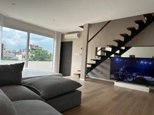 1 dormitorio con sofá, TV y escalera en Purobaires Hotel Boutique en Buenos Aires