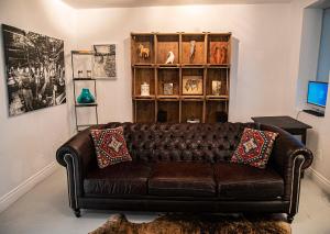 a brown leather couch in a living room with a book shelf at L'Hotel Particulier Griffintown in Montreal