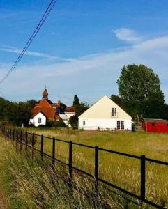 a field with a fence in front of a house at Wonderful rural dwelling- relax or explore Kent! in Kent