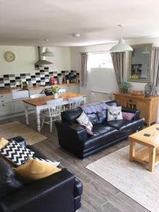 a living room with a black couch and a kitchen at Wonderful rural dwelling- relax or explore Kent! in Kent