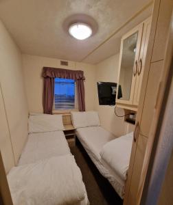 a small room with three beds and a window at Oasis S108 Caravan, Golden Palm Resort in Chapel Saint Leonards